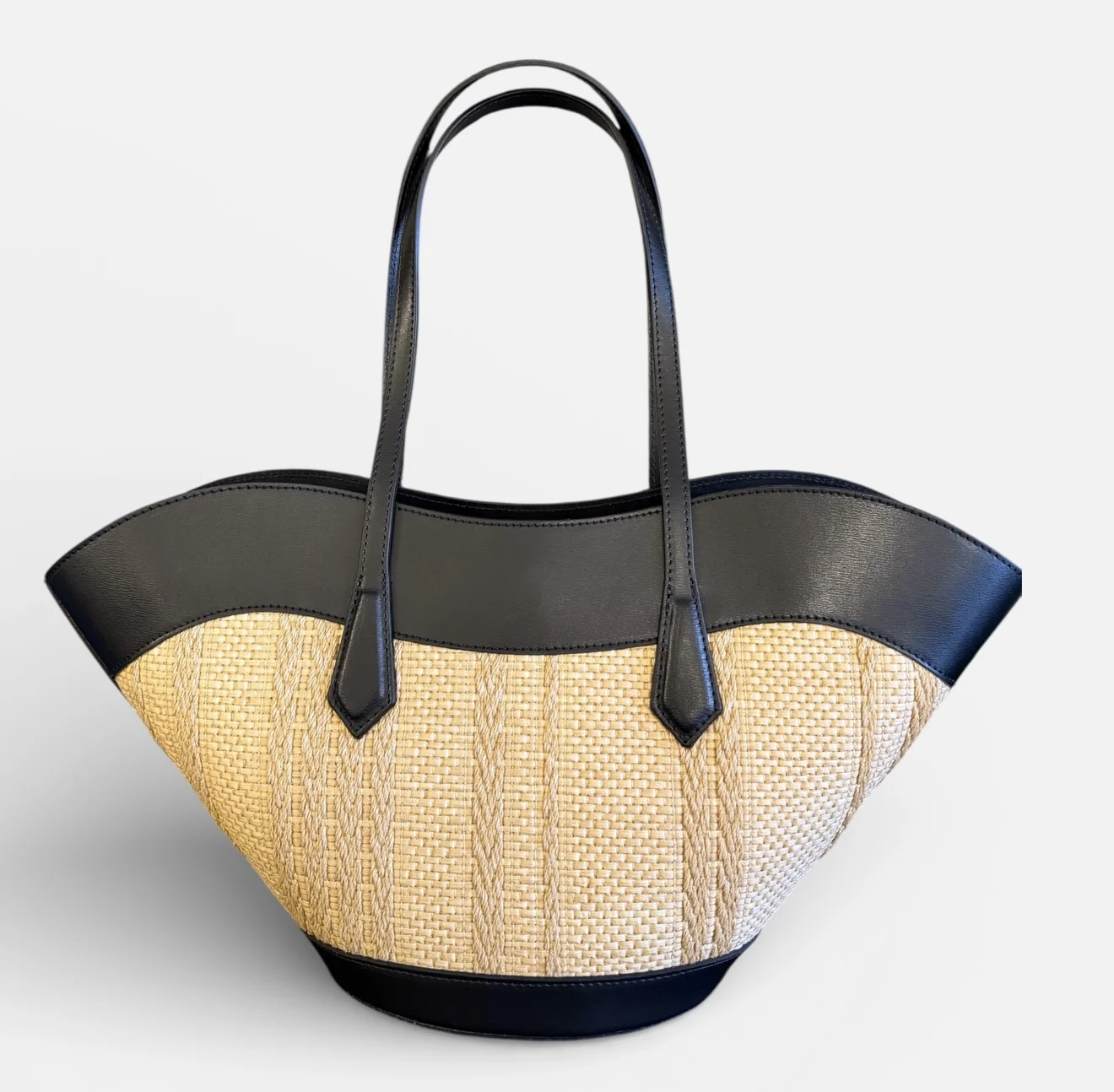 Bolso shopper tipo capazo de rafia trenzada con acabados y asas de piel de vacuno de alta calidad.