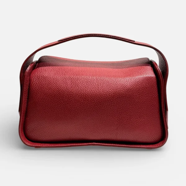 Bolso de mano estructurado de piel color granate con asa integrada y silueta curva moderna.