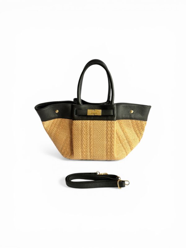 Bolso estilo tote confeccionado en rafia natural tejida con una franja superior de piel negra. Presenta una estructura blanda con lateralesn expandidos,asas cortas de mano y una correa bandolera desmontable a juego. En el centro destaca un cierre de broche metálico sobre una tira de piel.